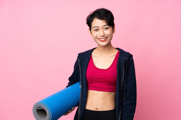 Jeune femme asiatique de sport avec un tapis et souriant