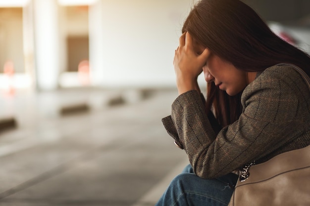 Une jeune femme asiatique stressée et mal de tête assise seule