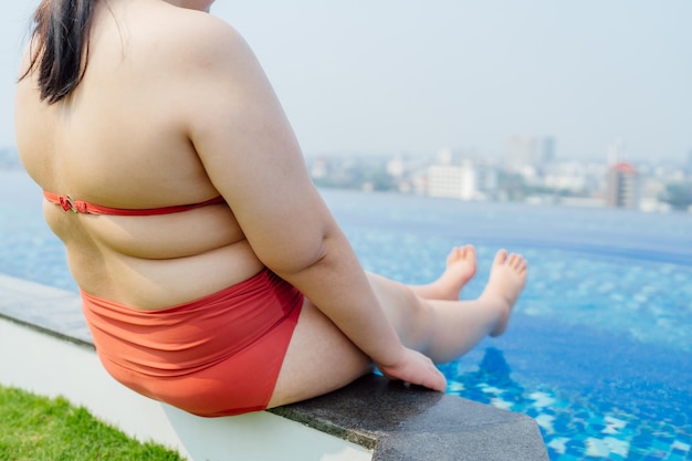 Jeune femme asiatique en surpoids portant un maillot de bain relaxant dans la piscine Heureuse femme taille plus gaie drôle Vacances Voyager en été