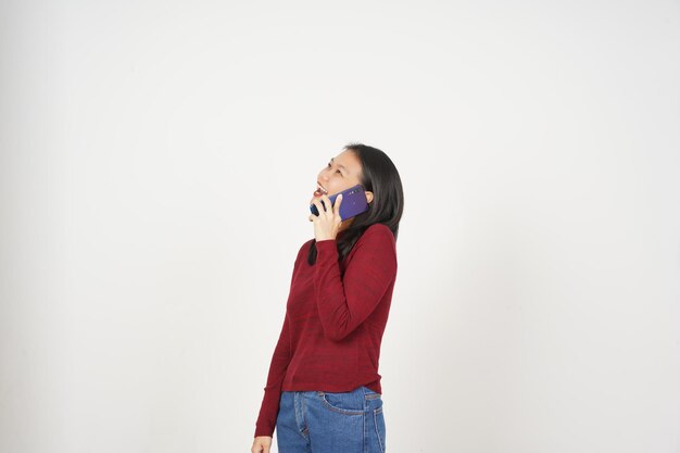 Une jeune femme asiatique en t-shirt rouge fait un appel téléphonique avec un smartphone isolé sur fond blanc