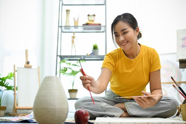 Jeune femme asiatique talentueuse et créative mesurant sa conception avec un pinceau