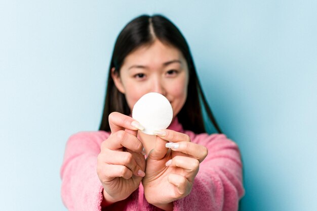 Jeune femme asiatique tenant un disque facial isolé sur fond rose