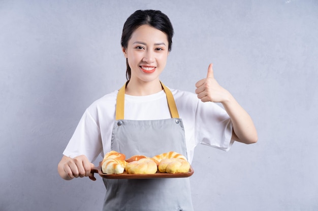 Jeune femme asiatique tenant du pain sur fond