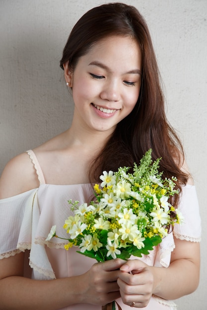 Jeune femme asiatique tenant des fleurs dans ses mains