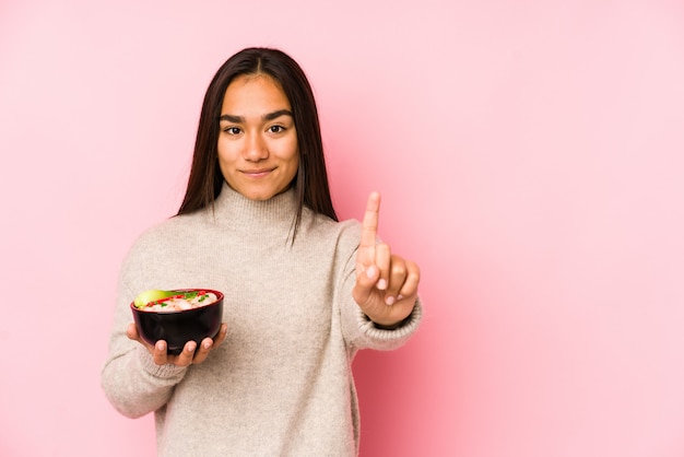 Jeune femme asiatique tenant une nouilles montrant le numéro un avec le doigt.