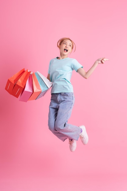 Jeune femme asiatique tenant un sac à provisions sur fond rose