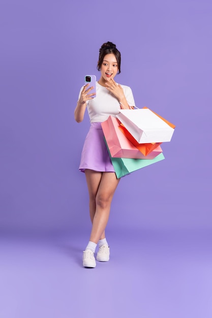Jeune femme asiatique tenant un sac à provisions sur fond violet