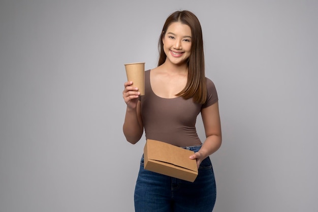 Jeune femme asiatique tenant une tasse de papier et une boîte en papier sur fond blanc Sauver le concept de la terre