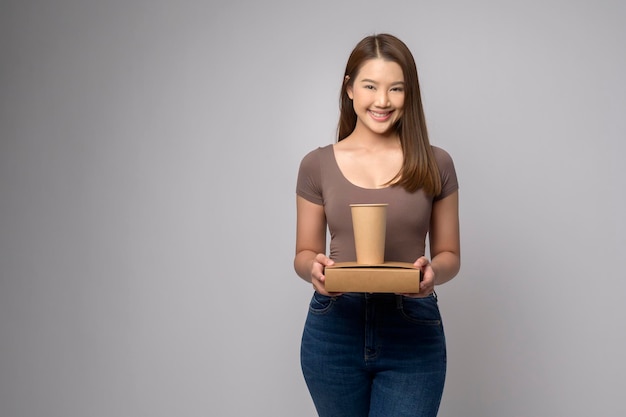 Jeune femme asiatique tenant une tasse de papier et une boîte en papier sur fond blanc Sauver le concept de la terre