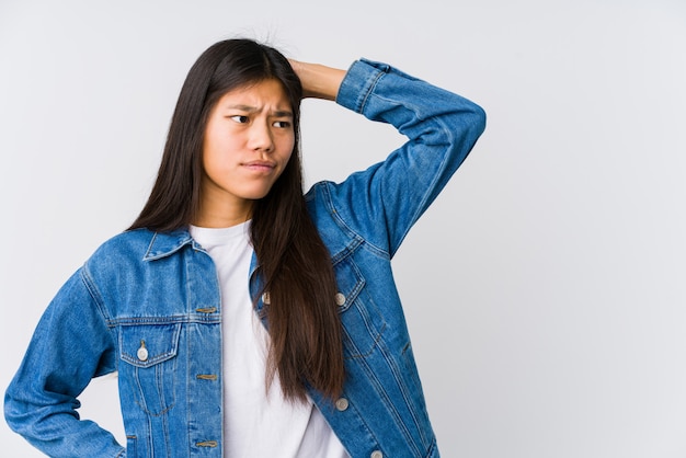 Jeune femme asiatique touchant l'arrière de la tête, pensant et faisant un choix.