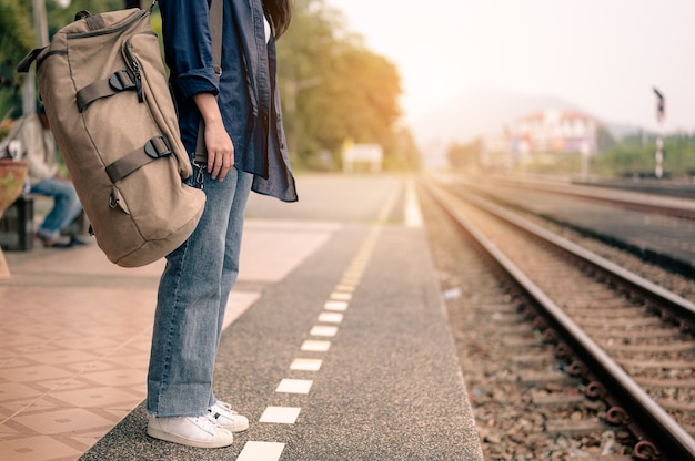 Jeune femme asiatique train d'attente sur la plate-forme ferroviaire. Concept de tourisme, de voyage et de loisirs.