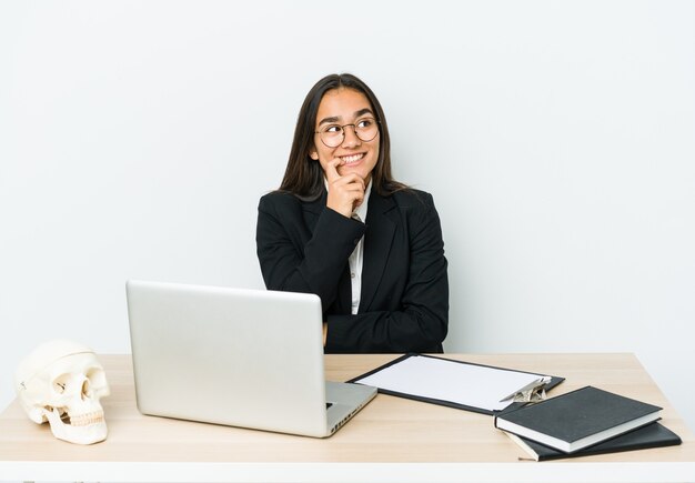 Jeune femme asiatique traumatologue isolée sur un mur blanc détendu penser à quelque chose en regardant un espace de copie.