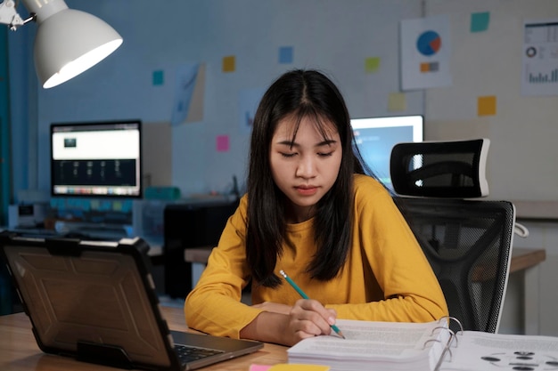 Jeune femme asiatique travaillant et apprenant la nuit au bureau à domicile.