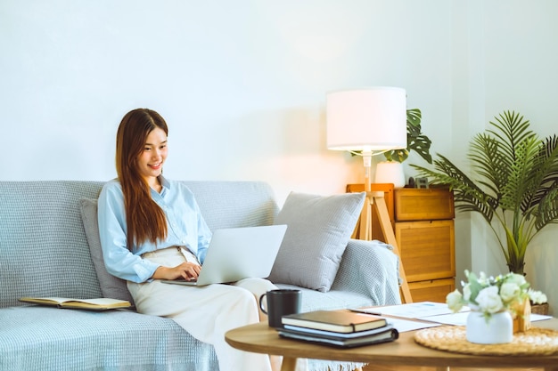 Photo jeune femme asiatique travaillant à domicile à l'aide d'un ordinateur et buvant du café dans sa chambre document finance et conférence réunion en ligne pour de nouveaux projets