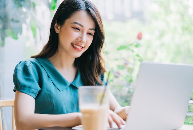 Jeune femme asiatique utilisant un ordinateur portable au café