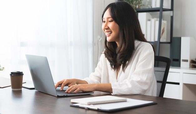 Jeune femme asiatique utilisant un ordinateur portable avec un travail créatif au bureau à domicile.