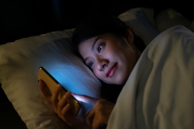 Jeune femme asiatique utilisant un smartphone à minuit