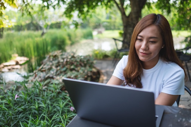 Une jeune femme asiatique utilisant et travaillant sur un ordinateur portable dans le parc