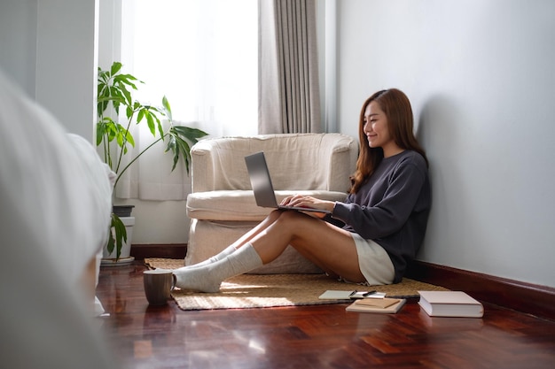 Une jeune femme asiatique utilisant et travaillant sur un ordinateur portable à la maison