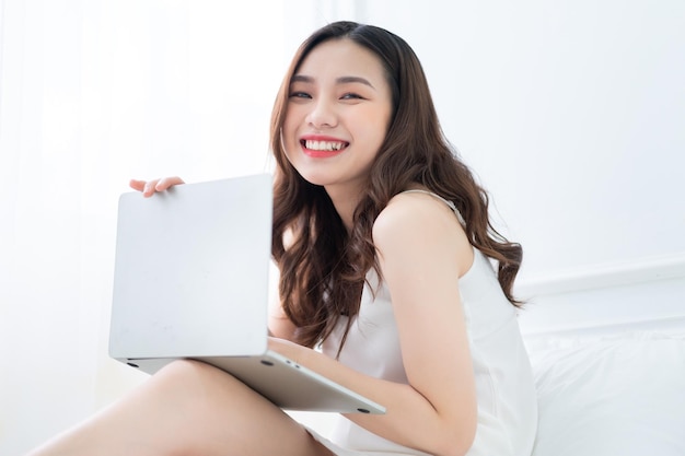 jeune, femme asiatique, utilisation, ordinateur portable, dans lit