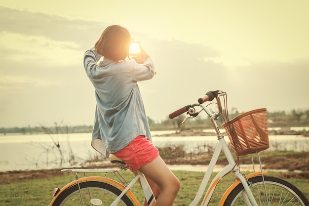 Jeune femme asiatique à vélo regarder main vue cadre coucher de soleil