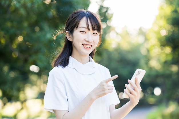 Jeune femme asiatique en vêtements blancs avec un smartphone