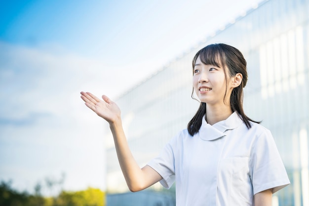 Jeune femme asiatique en vêtements d'infirmière et posant avec les mains