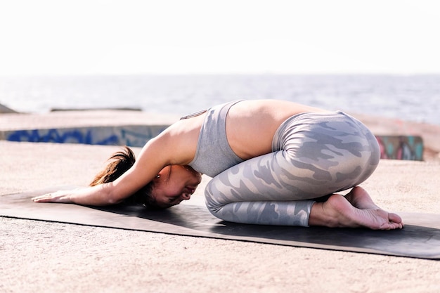 Une jeune femme asiatique en vêtements de sport pratiquant le yoga.