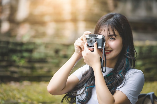 Jeune femme asiatique voyageur souriant tout en voyageant autour de l'ancien temple thaïlandais en vacances.