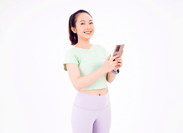 Jeune femme d'Asie montre un écran de téléphone intelligent vide avec des sourires d'expression positive largement vêtus de vêtements décontractés se sentant heureux sur fond bleu Téléphone portable avec écran blanc dans la main féminine