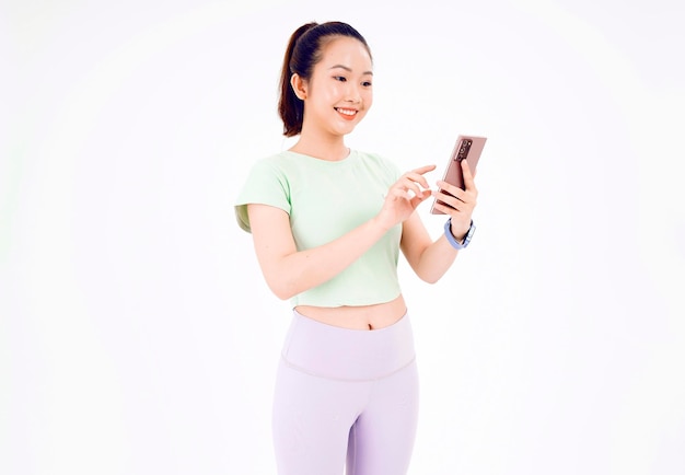 Jeune femme d'Asie montre un écran de téléphone intelligent vide avec des sourires d'expression positive largement vêtus de vêtements décontractés se sentant heureux sur fond bleu Téléphone portable avec écran blanc dans la main féminine