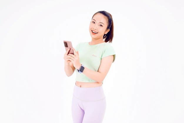 Jeune femme d'Asie montre un écran de téléphone intelligent vide avec des sourires d'expression positive largement vêtus de vêtements décontractés se sentant heureux sur fond bleu Téléphone portable avec écran blanc dans la main féminine