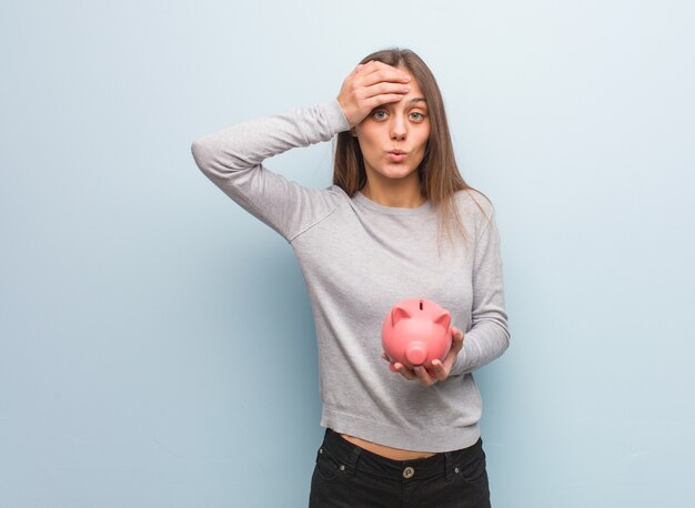 Jeune femme assez caucasienne inquiète et dépassée. Elle tient une tirelire.