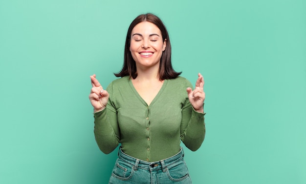 Jeune femme assez décontractée souriant et traversant anxieusement les deux doigts, se sentant inquiet et souhaitant ou espérant bonne chance