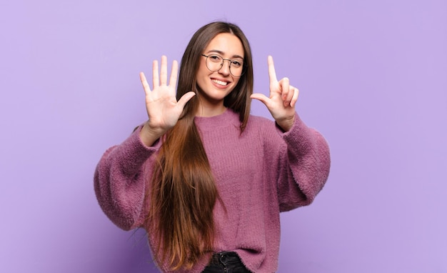 Jeune femme assez décontractée souriante et semblant amicale, montrant le numéro sept ou septième avec la main en avant, comptant à rebours