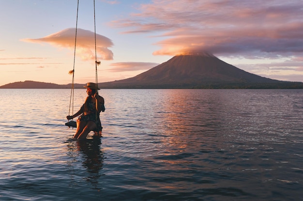 Une jeune femme assise sur une balançoire pendant un beau coucher de soleil sur l'île d'Ometepe au Nicaragua