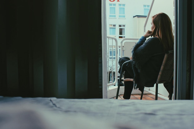 Une jeune femme assise sur le balcon à la maison.
