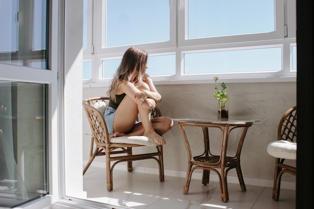 Une jeune femme assise sur le balcon rencontre le matin La fille solitaire est triste en regardant par la fenêtre