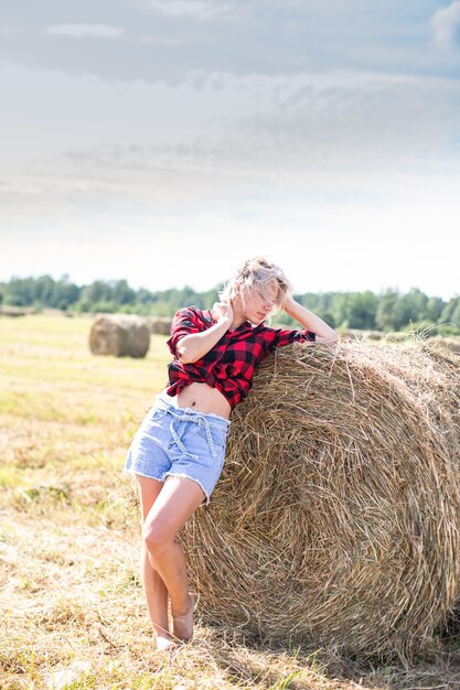 Photo jeune femme assise sur une balle de foin. photo de haute qualité