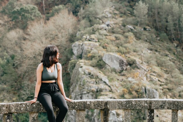 Jeune femme assise sur un banc au milieu d'une forêt à l'écart