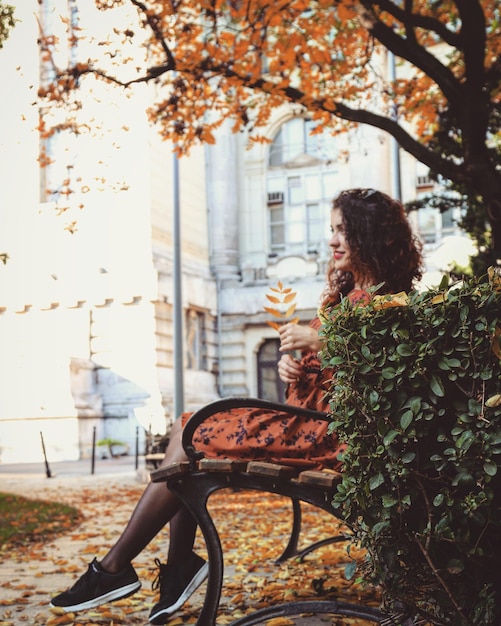 Photo une jeune femme assise sur un banc en automne.