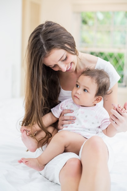 Jeune femme assise avec bébé sur le lit