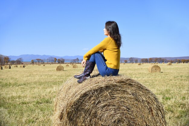 Jeune femme assise sur une botte de foin dans le domaine