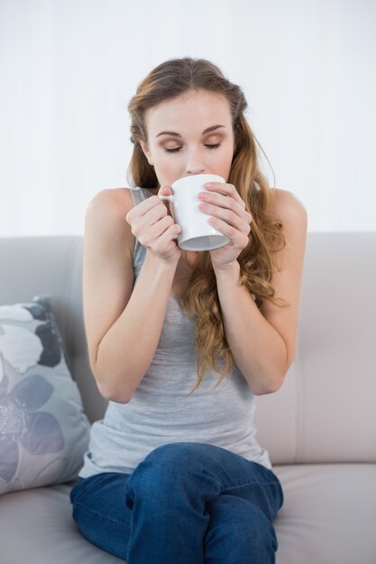 Jeune femme assise sur un canapé à boire de la tasse