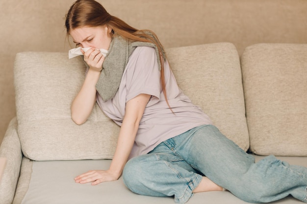 Une jeune femme assise sur le canapé à la maison.