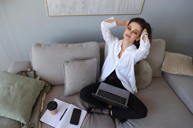 Jeune femme assise sur le canapé et se reposant après une journée à la maison Travail à distance pendant une pandémie