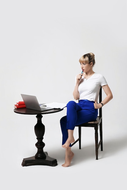 Une jeune femme assise sur une chaise sur un fond blanc