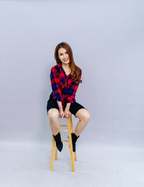 La jeune femme assise sur la chaise a souri joyeusement avec la séance photo. Concept