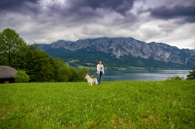 Jeune femme assise avec un chien husky sibérien dans les montagnes