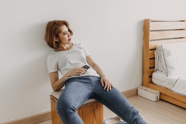 Une jeune femme assise contre le mur à la maison.
